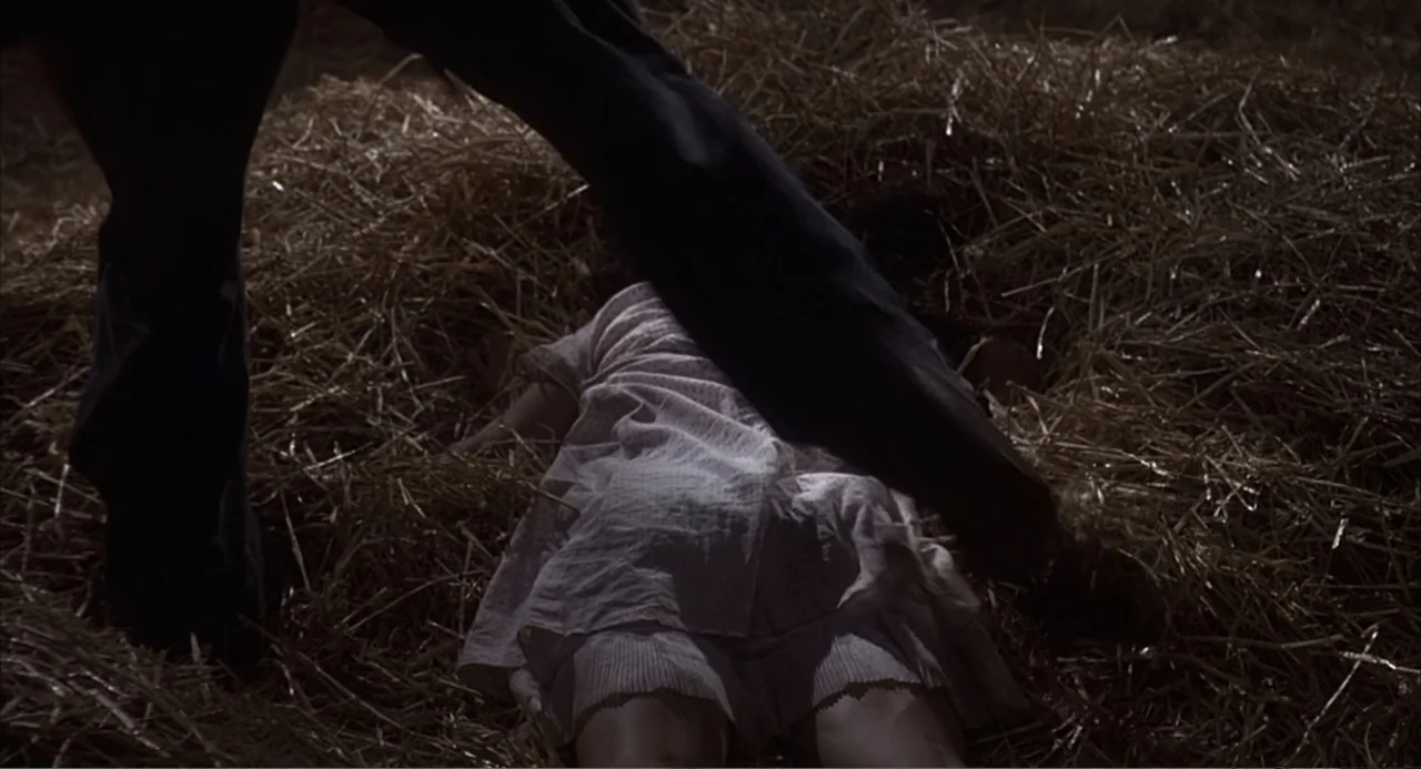 Of Mice and Men (1992) movie still: medium — A dimly lit barn interior features loose golden-brown straw scattered across the ground. A person…