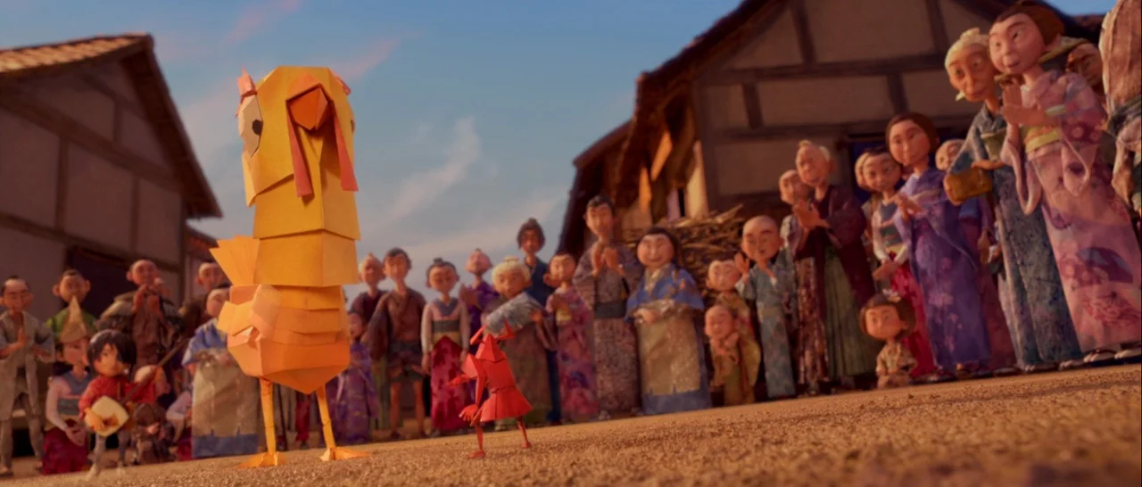 Kubo and the Two Strings movie still: fullbody — A group of villagers stands in a dusty square watching a performance. A young boy plays an…