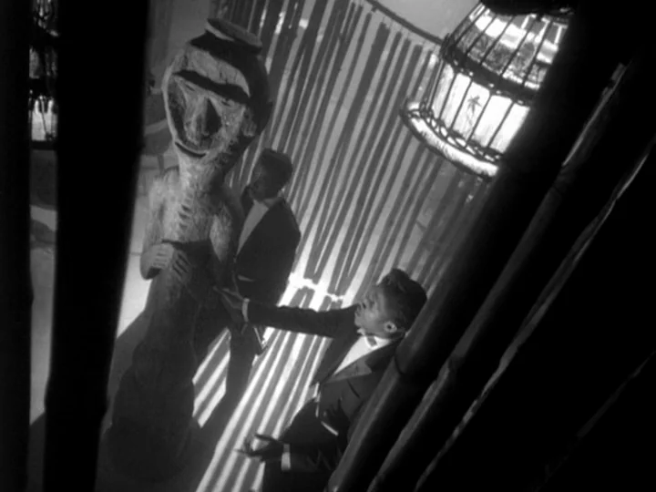 I Am Cuba (1964) movie still: medium — A dimly lit room features bamboo dividers casting striped shadows over the floor. Two men in formal evening…
