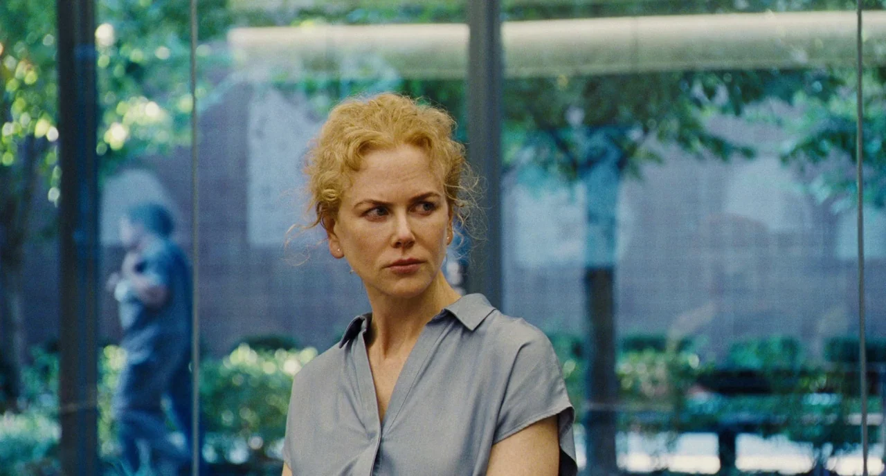 The Killing of a Sacred Deer (2017) movie still: medium — A woman stands within a modern glass atrium with foliage visible through the panes. The…