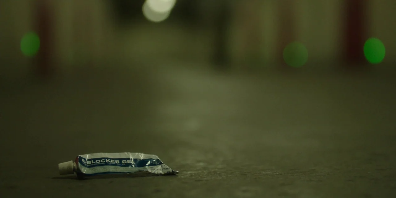 The Girl With All The Gifts (2016) movie still: closeup — A discarded tube of ointment rests on the grey concrete floor of a parking garage. The…