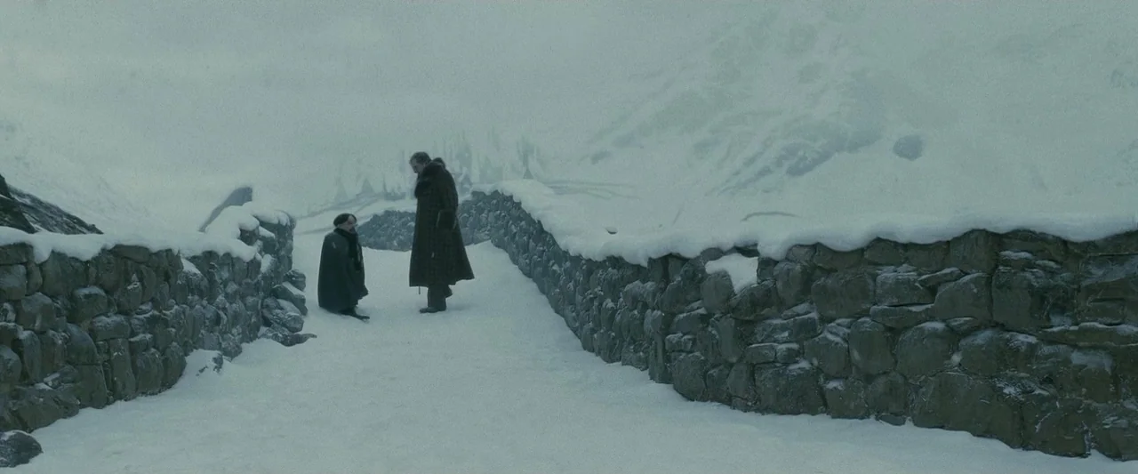 Harry Potter & The Half Blood Prince (2009) movie still: wide — A stone bridge sits amidst a vast, snow-covered landscape under a pale sky. Two men…