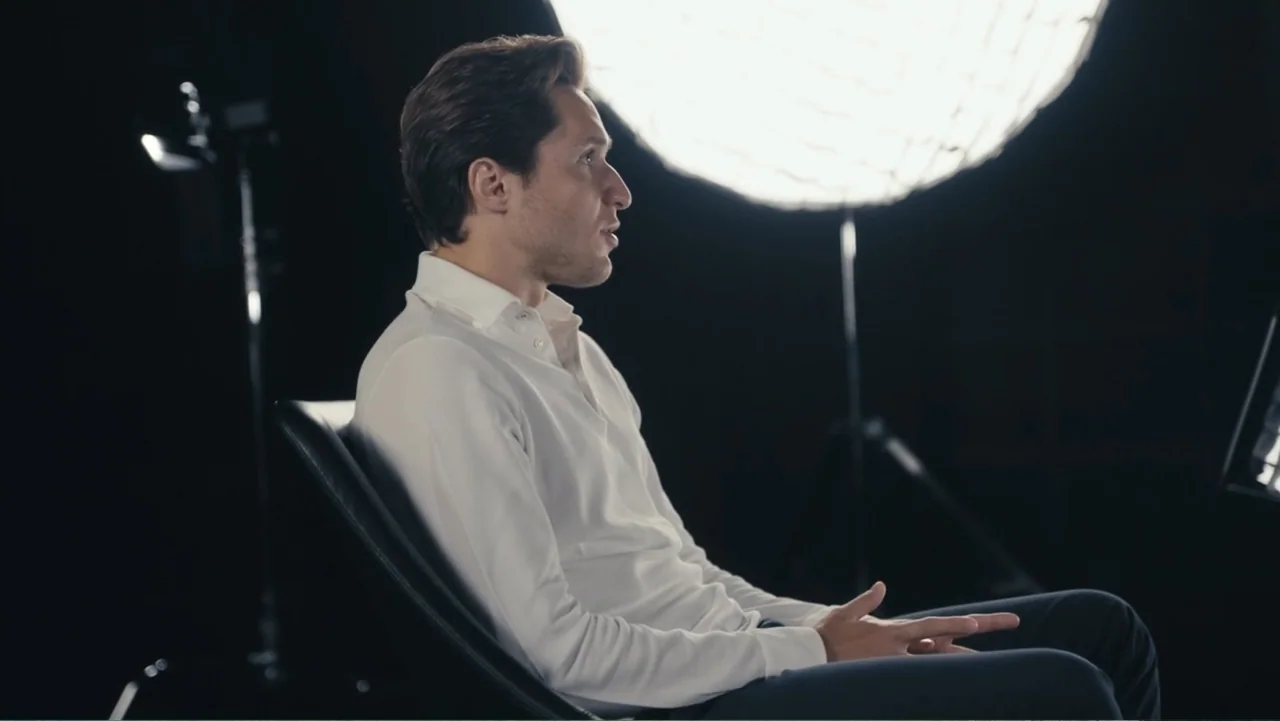 Federico Chiesa - Back on Track (2023) movie still: medium — A dark studio environment features a black background with a large circular light…