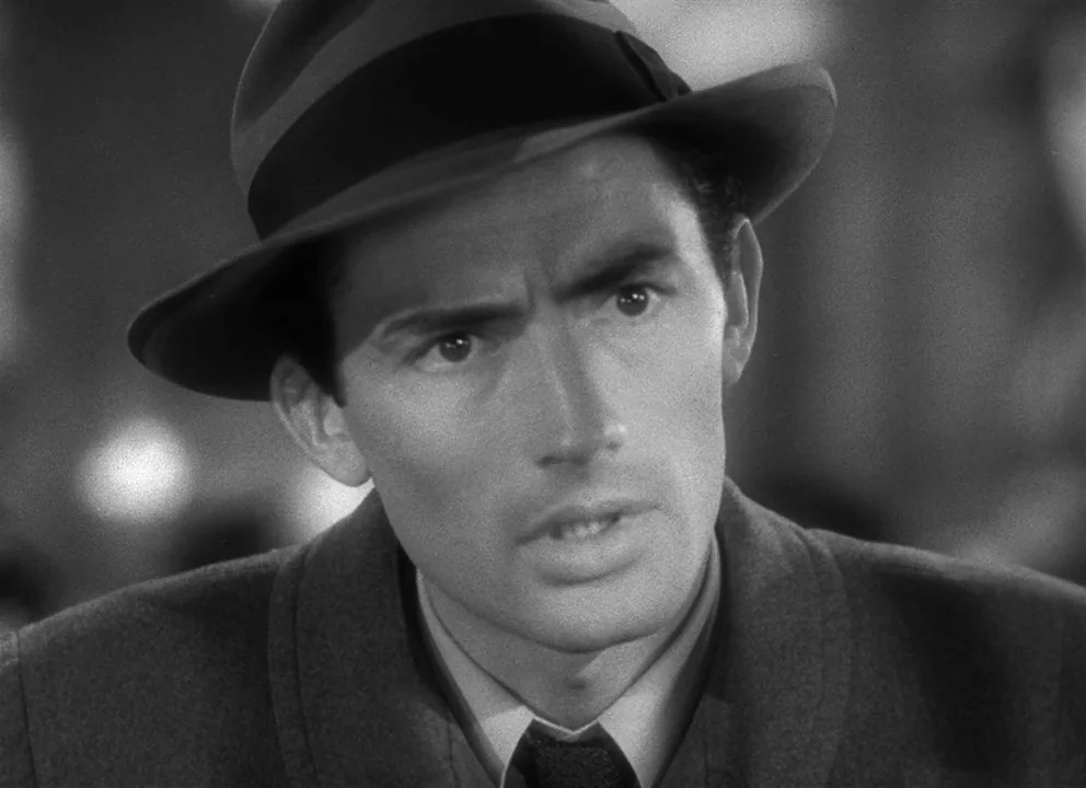 Spellbound (1945) movie still: closeup — An interior space with a blurred, indistinct background showing light reflections. A man wearing a fedora…