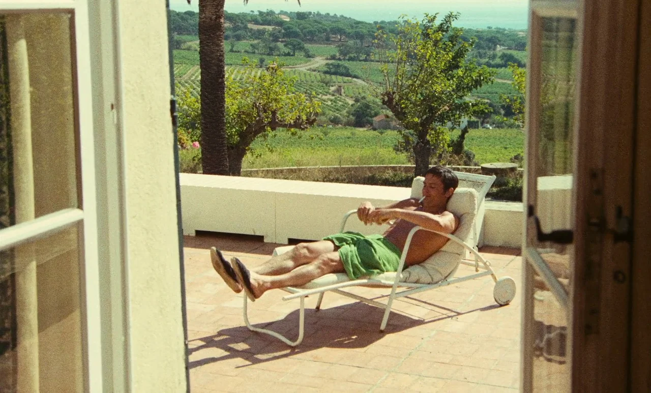 The Swimming Pool (1969) movie still: fullbody — A sunny stone terrace overlooks a sprawling landscape of rolling hills and vineyards. A man…