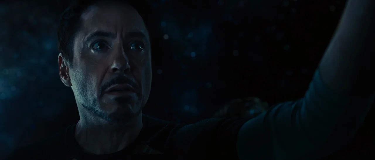 Avengers: Age of Ultron (2015) movie still: closeup — A man drifts through the dark void of deep space surrounded by faint stars. He gazes off into…