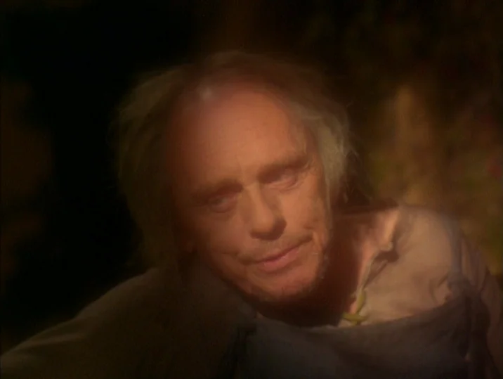 Twilight of the Ice Nymphs (1997) movie still: closeup — A dimly lit room with rough wooden surfaces and shadowy corners. An elderly man looks…