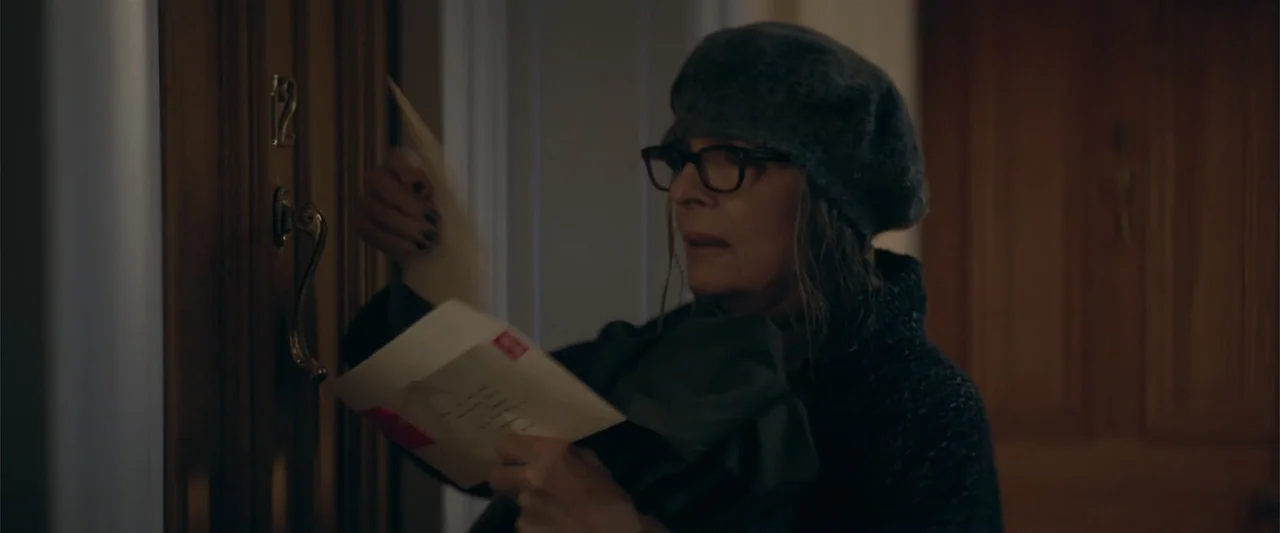Hampstead (2017) movie still: medium — A dimly lit residential hallway features a wooden door labeled with the number twelve. An older woman with…