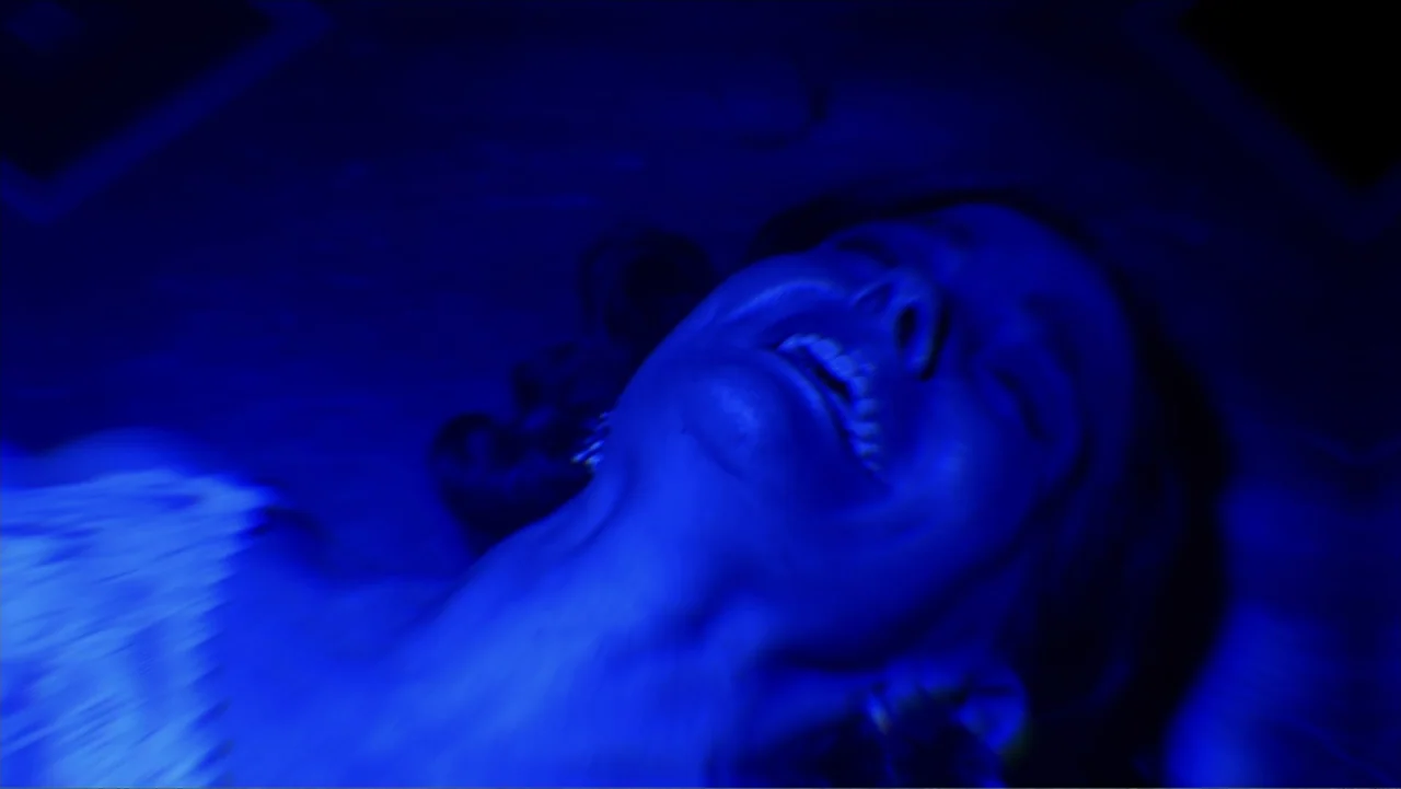 Alien Abduction: Betty and Barney Hill (2022) movie still: closeup — A dimly lit interior space with the subject reclining in darkness. A woman with…