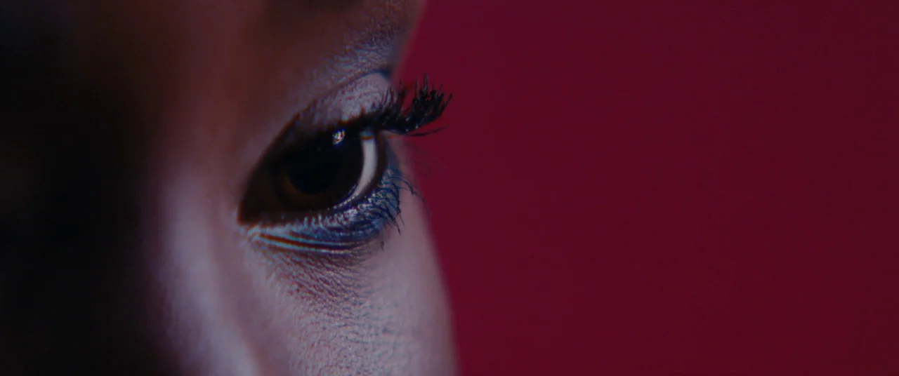 Girlhood (2014) movie still: closeup — An extreme close-up focuses on a woman's eye set against a solid magenta background. The subject is oriented…