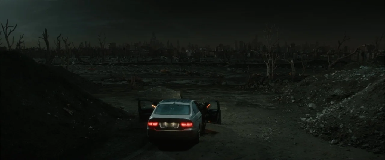 Breathe (2011) movie still: wide — A desolate barren wasteland stretches toward a darkened silhouette of a distant ruined city. A solitary vehicle…