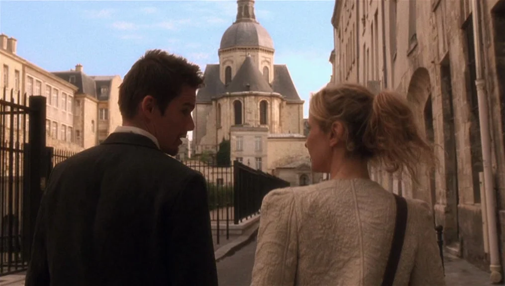 Before Sunset (2004) movie still: medium — A European stone-paved street is lined with historic buildings and an ornate church dome. A man and a…