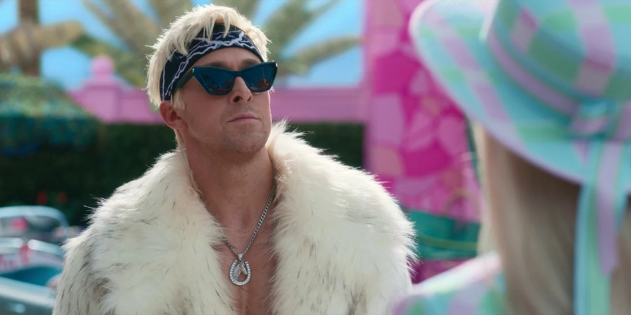 Barbie (2023) movie still: medium — A sunny outdoor setting featuring vibrant pink walls and architectural elements in the background. A man wearing…