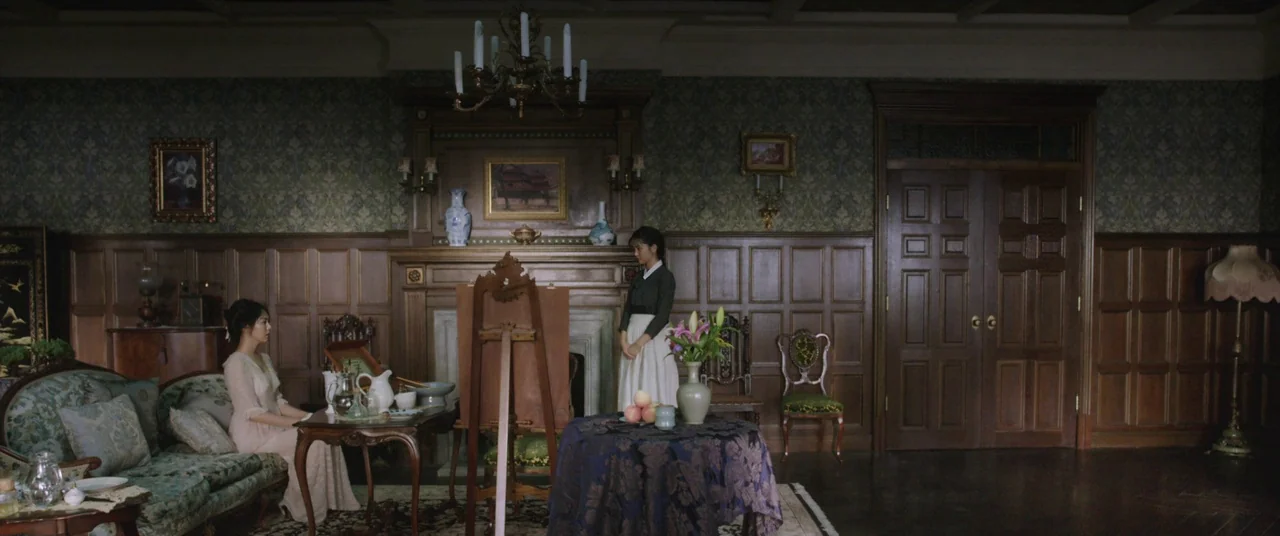 The Handmaiden (2016) movie still: wide — A refined parlor features wood-paneled walls, intricate wallpaper, and vintage furniture arranged…