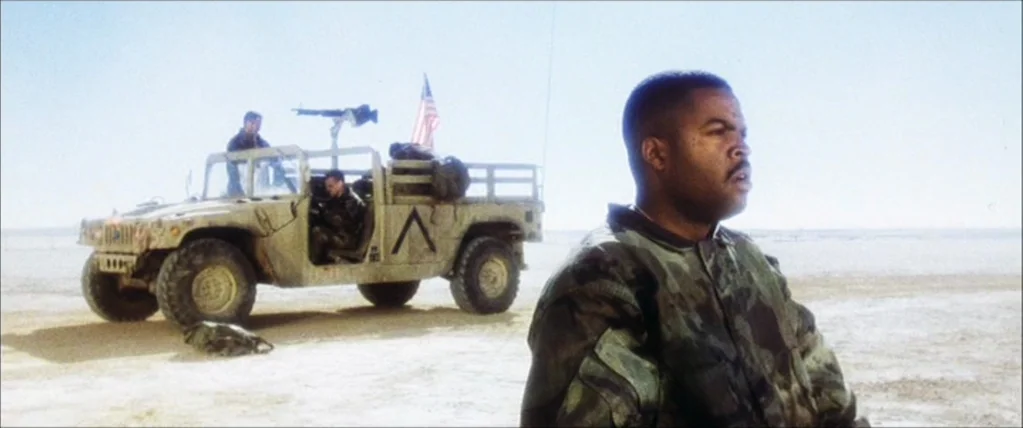 Three Kings (1999) movie still: medium — A vast, sun-bleached desert expanse features a tan military Humvee parked in the distance. A soldier in…
