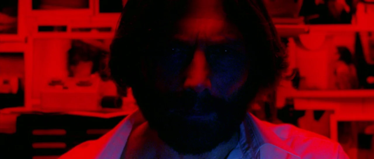 The Strange Colour of Your Body’s Tears (2013) movie still: closeup — A dark space is filled with bright red light coming from multiple monitor…