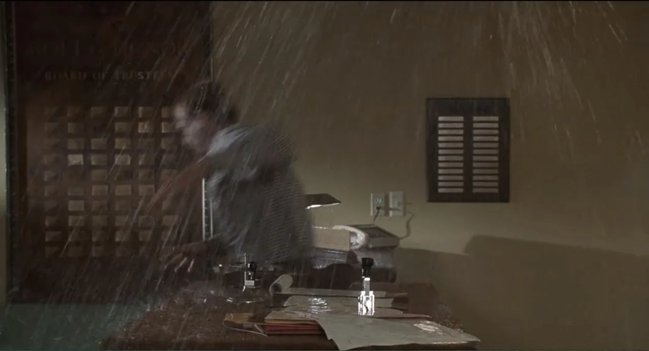 National Lampoon's Van Wilder (2002) movie still: medium — A dimly lit office features water pouring down from above onto a wooden desk. A person…