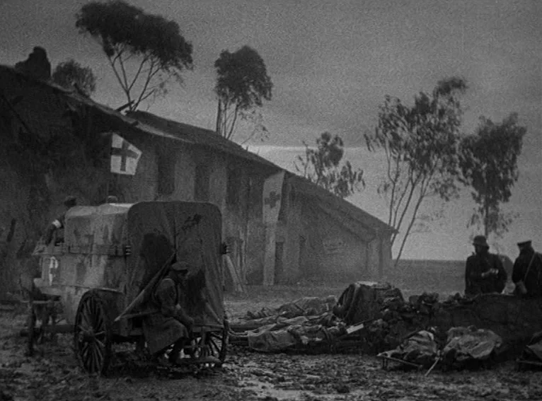 All Quiet on the Western Front (1930) movie still: wide — A war-torn field hospital is marked by flags with red crosses under a gray sky. Soldiers…
