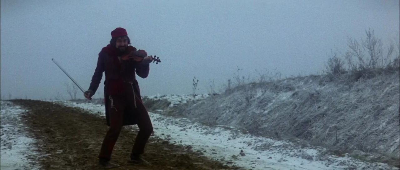 Fiddler On The Roof (1971) movie still: fullbody — A snowy, muddy road extends through a foggy, barren landscape under a gray sky. A bearded man in…