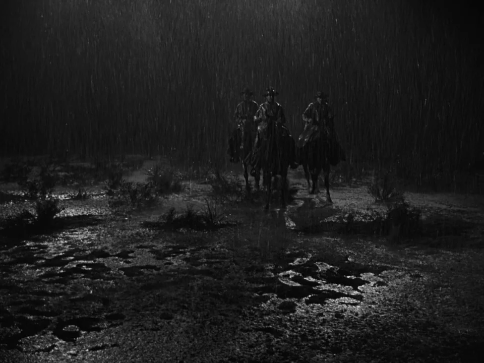 My Darling Clementine (1946) movie still: wide — Three riders on horseback approach through a torrential downpour on flat, muddy terrain at night.…