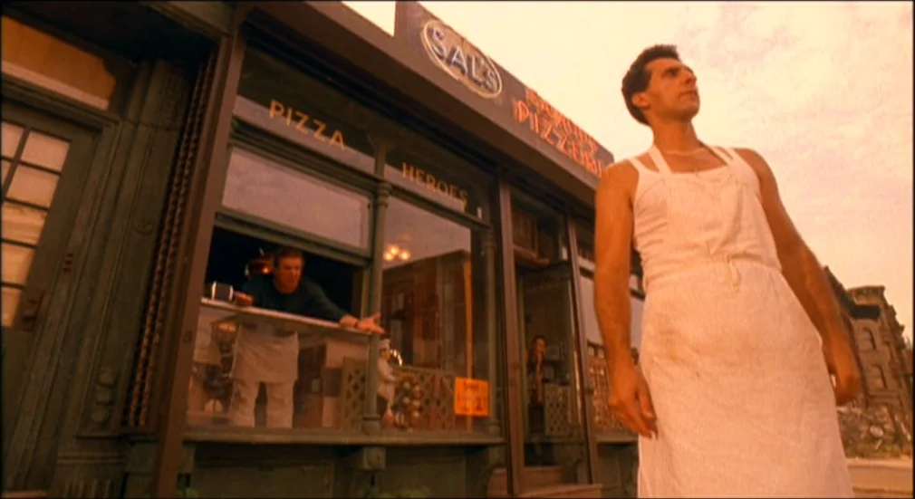 Do The Right Thing (1989) movie still: fullbody — A Brooklyn pizzeria storefront features large windows and a faded sign reading Sal's. One man…