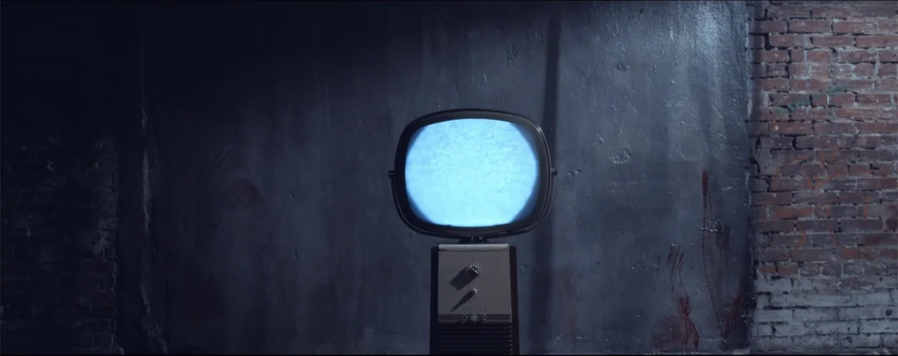 El Último Juego (2025) movie still: medium — A dark, gritty interior space features a brick wall partially covered in stained concrete. A vintage…