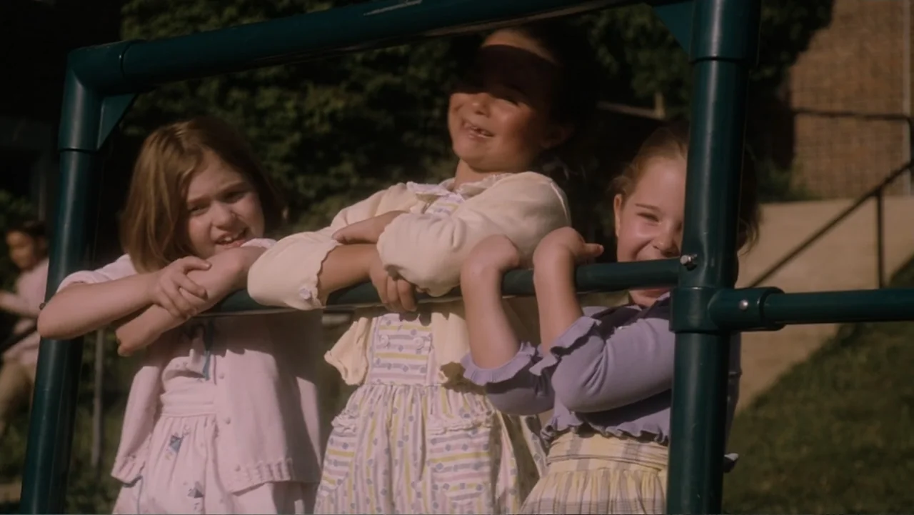 Flipped (2010) movie still: medium — Three young girls stand behind a green metal frame in an outdoor area. They lean forward against the bar while…