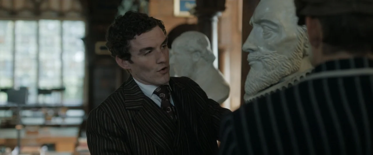 Young Sherlock Holmes (1985) movie still: medium — A wood-paneled room contains multiple white marble busts on stands near a window. A man in a…