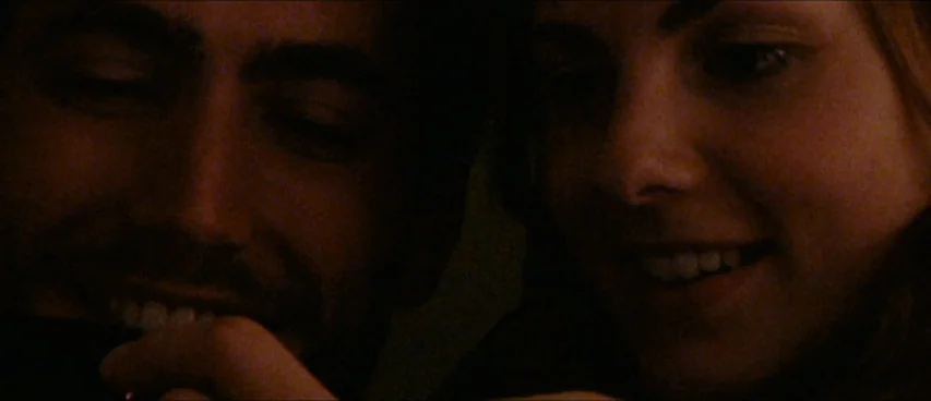 This Movie Is Broken (2010) movie still: closeup — A dimly lit room provides the backdrop for a close-up of two individuals. The man and woman are…