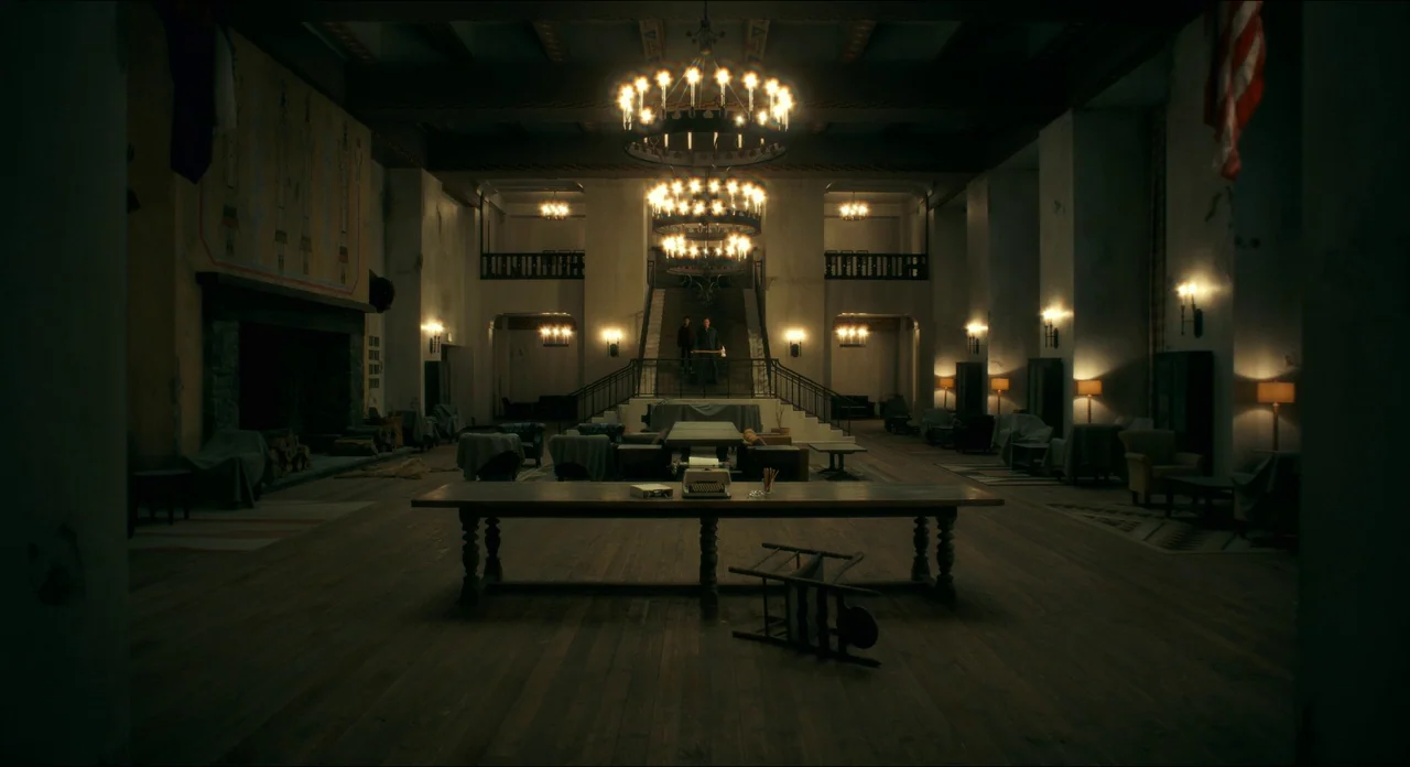 Doctor Sleep movie still: establishing — A cavernous hotel lobby features a grand staircase and high ceilings with large chandeliers. A central long…