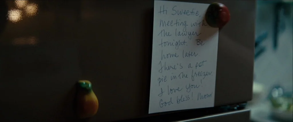 Let Me In (2010) movie still: closeup — A white paper note is taped to the dark metallic surface of a refrigerator. The note contains handwritten…