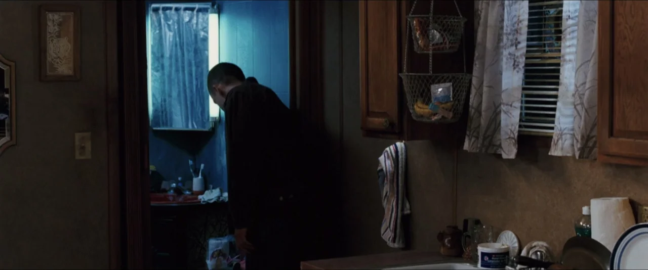 Black Snake Moan (2006) movie still: medium — A cramped trailer interior features wood paneling and a cluttered bathroom visible through a doorway.…