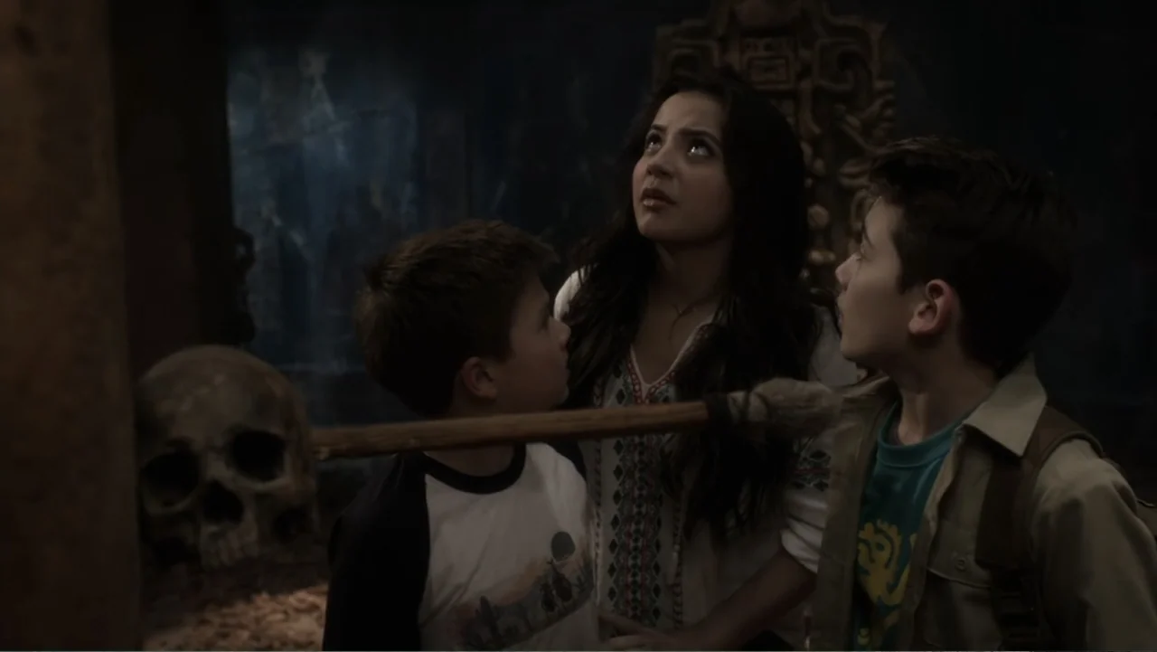 Legends of the Hidden Temple (2016) movie still: medium — A dark ancient chamber features stone walls and a prominent carved stone skull artifact. A…