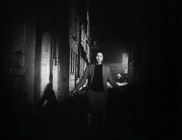 Dementia (Daughter of Horror) (1955) movie still: fullbody — A dark, narrow alleyway at night features tall brick walls and minimal ambient light. A…