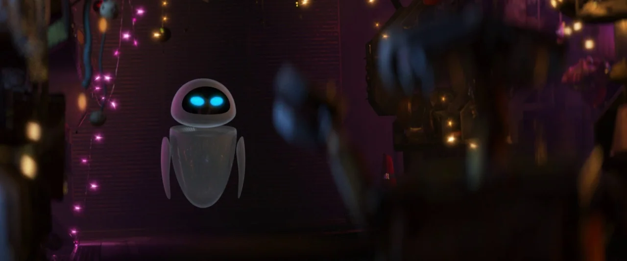 Wall-E (2008) movie still: medium — A cluttered dark space filled with discarded scrap and hanging strands of pink string lights. A small sleek…