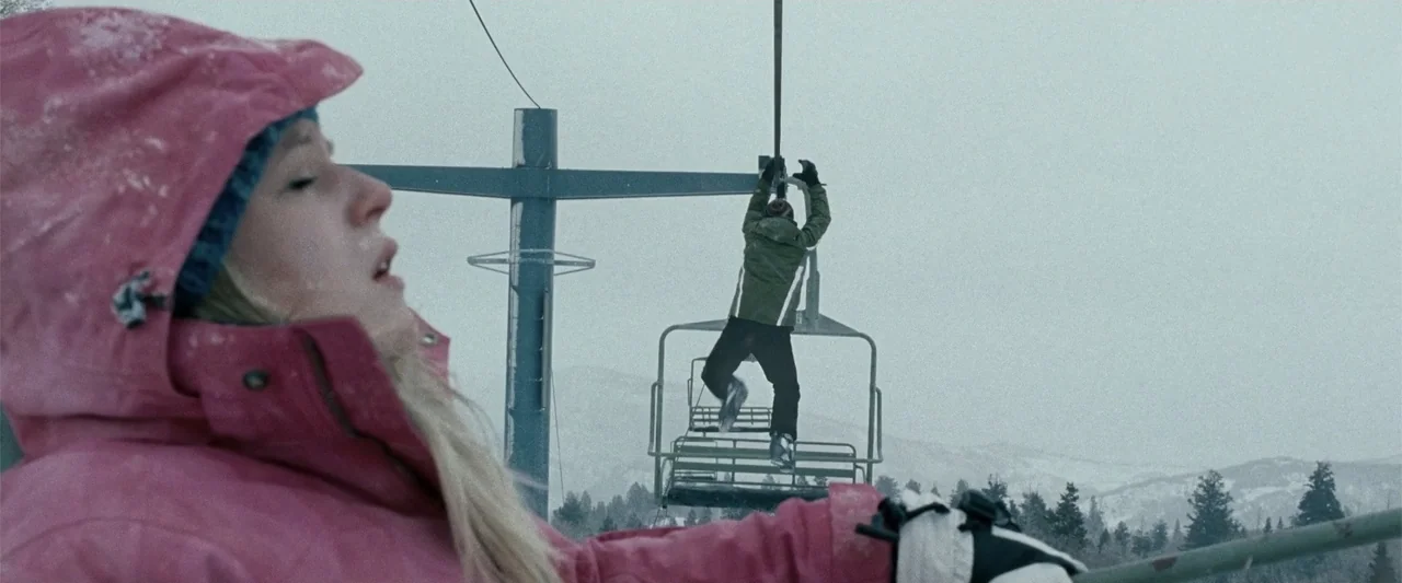 Frozen (2010) movie still: medium — A snowy mountain landscape features a metal chairlift extending into the overcast gray sky. A woman in a pink…