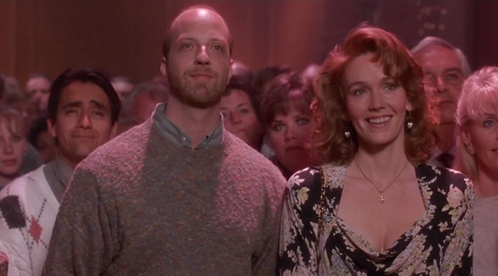 Groundhog Day (1993) movie still: medium — A crowded auditorium filled with people sitting in rows during a formal event. A man and a woman in the…