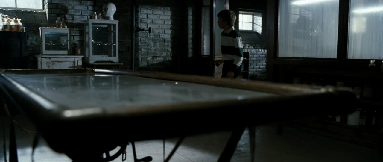 The Haunting in Connecticut (2009) movie still: medium — A dark, brick-walled room contains a large central examination table and medical glass…
