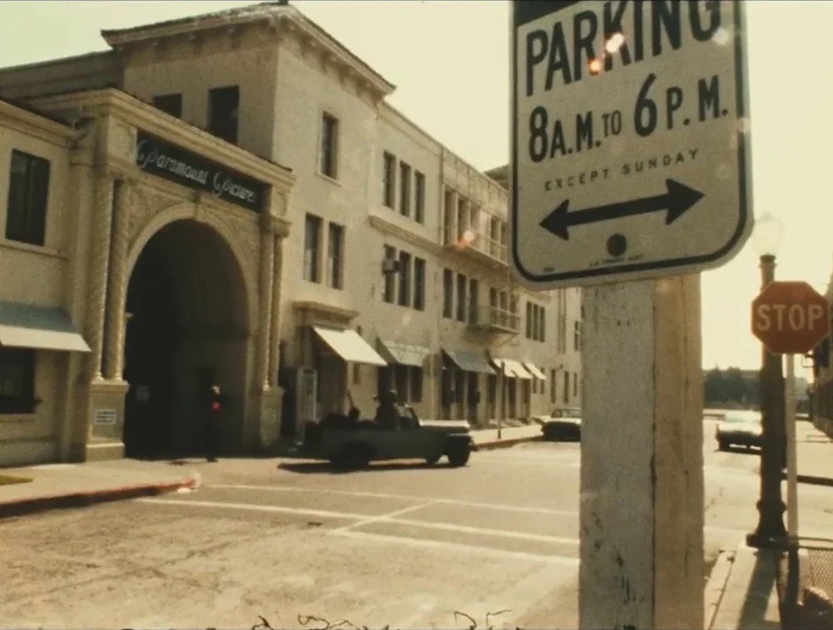 The Other Side of the Wind (2018) movie still: wide — The historic entrance gate of a movie studio sits adjacent to a paved intersection. A metal…