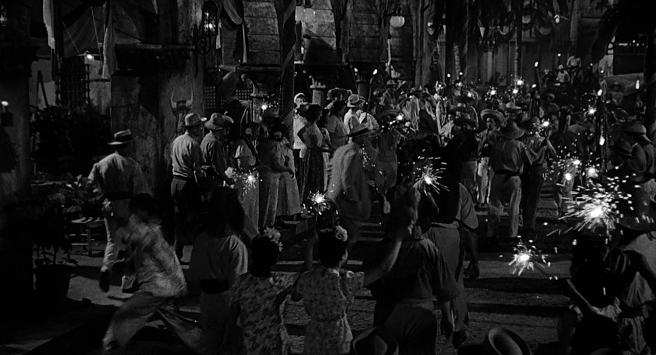Dead Men Don’t Wear Plaid (1982) movie still: wide — A bustling street festival at night is decorated with flags and banners. A large group of…