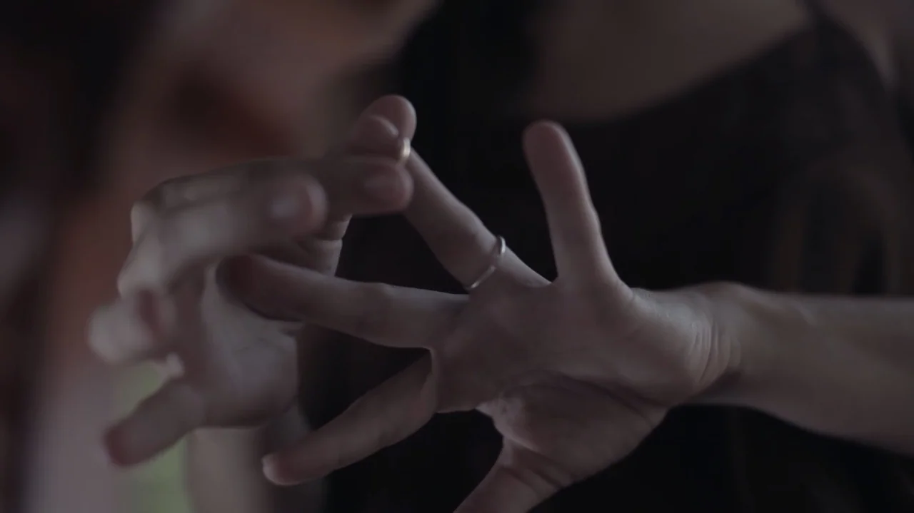 Still Life (2013) movie still: closeup — A close-up view shows two hands positioned near each other against a dark background. One finger wears a…