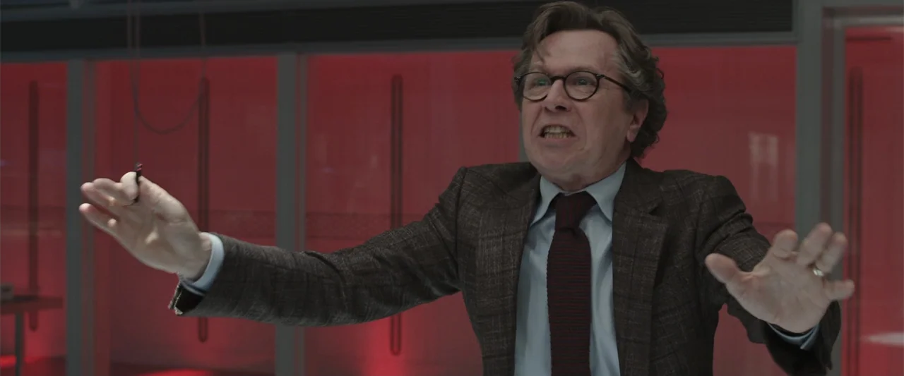 RoboCop (1987) movie still: medium — A modern office space features a wall of bright red glass panels. A man in a blazer stands before the glass and…