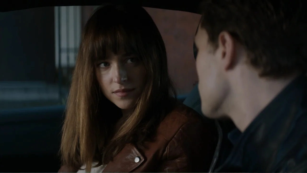 Fifty Shades of Grey (2015) movie still: medium — Two people sit inside a vehicle during the daytime. A woman turns her head to look at the man…