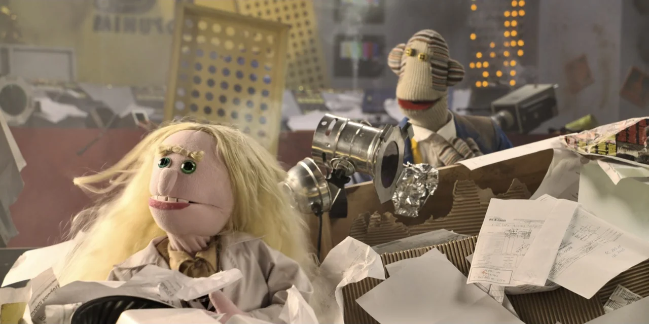 31 Minutes: One Hot Christmas (2025) movie still: medium — An cluttered office desk covered in piles of white paper and office documents. Two…