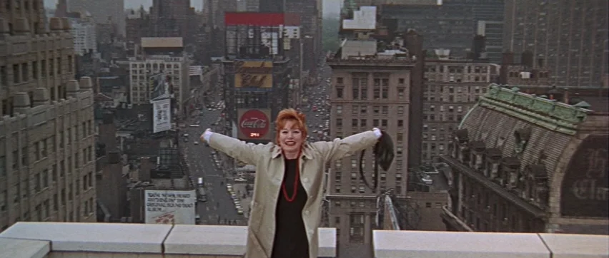 Sweet Charity (1969) movie still: medium — A woman stands on a rooftop overlooking a dense urban cityscape with high-rise buildings. She stands with…