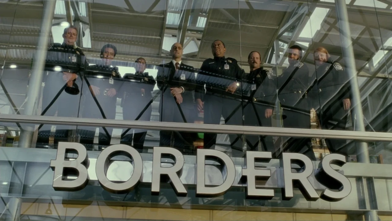 The Terminal (2004) movie still: medium — A glass mezzanine overlooks a bookstore interior with high ceilings and metal supports. Seven security…