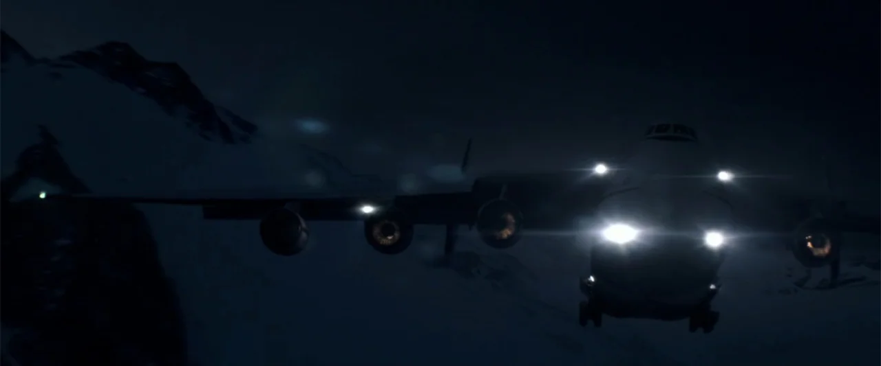 2012 (2009) movie still: wide — A large military transport plane maneuvers low above dark snow-covered mountain ridges at night. The aircraft…