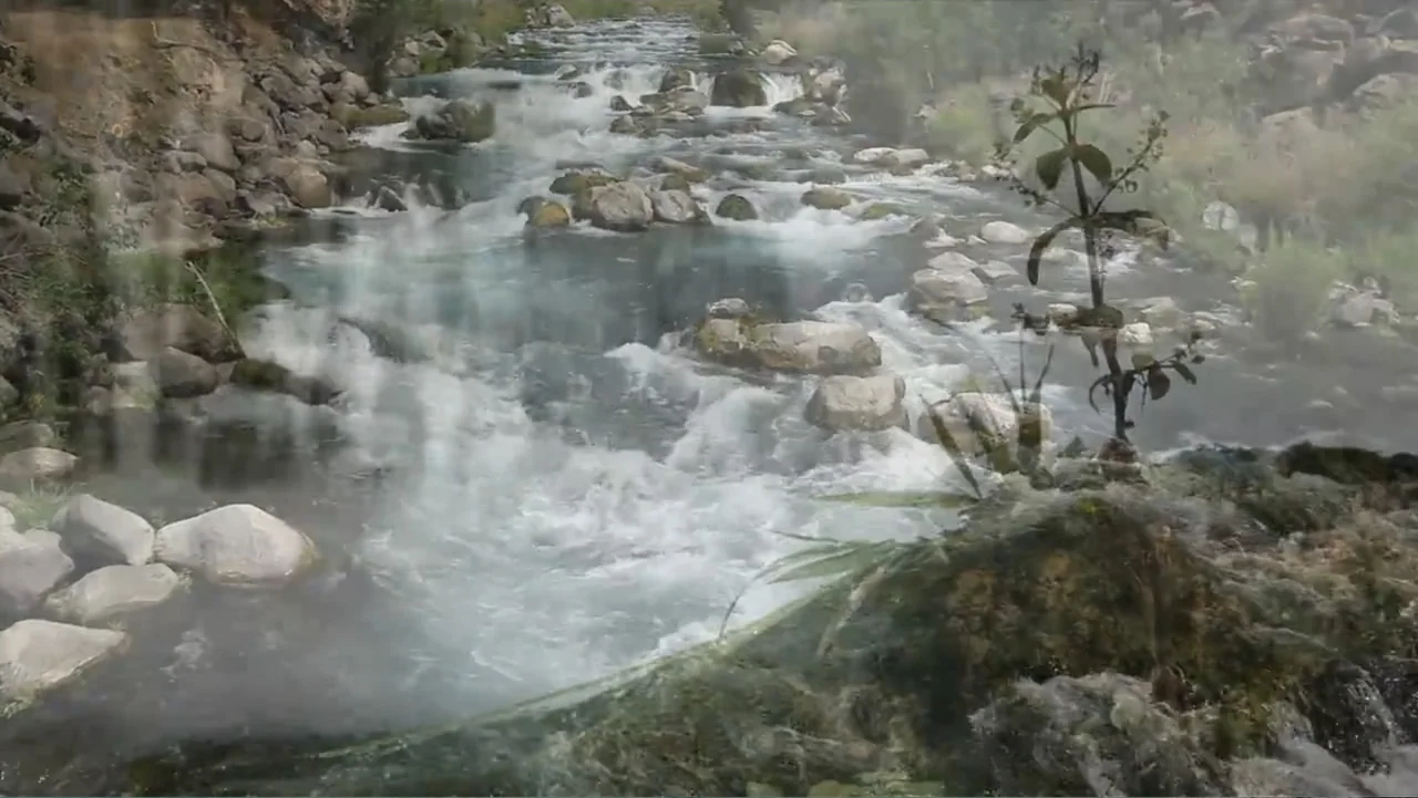Idaho: The Movie (2012) movie still: establishing — A rocky riverbed flows with turbulent water through a natural outdoor landscape. Transparent…