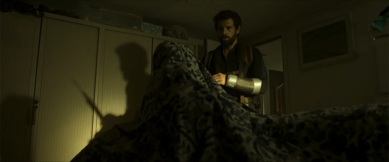 Apocalypse Z: The Beginning of the End (2024) movie still: medium — A dimly lit room with large storage cabinets and a floral print blanket…