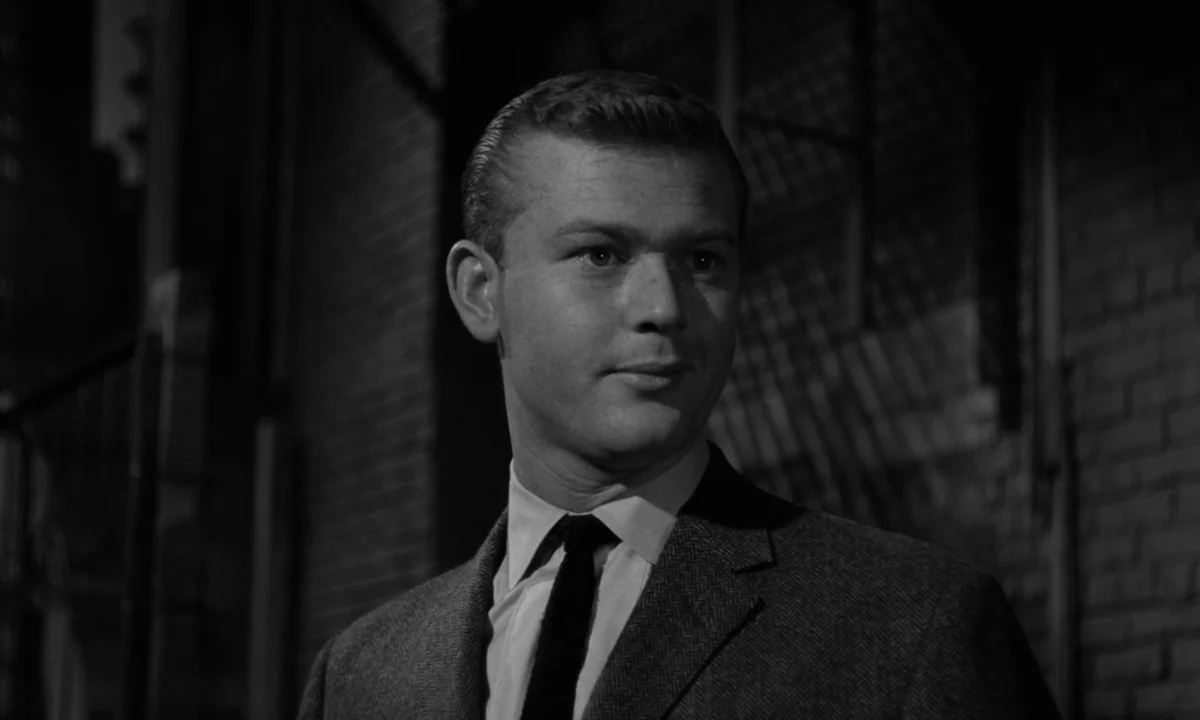 Sweet Smell of Success (1957) movie still: closeup — A man stands in front of a dark brick wall at night. The man looks off-camera to the right.